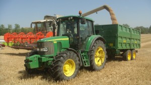Remolque agrícola tándem de laterales cosechando con tractor John Deere