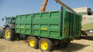 Remolque agrícola tándem de laterales cosechando con tractor John Deere